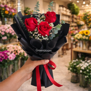 red rose bouquet with baby’s breath wrapped in black paper held by hand in a flower shop – romantic flower delivery Lebanon Greenbloom florist